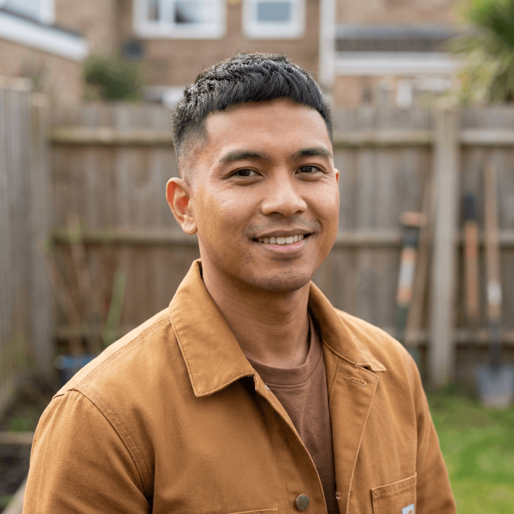 Male business owner in his late 50s South Asian in factory setting with friendly expression