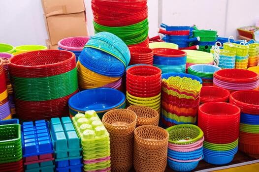 Stacks of colorful plastic baskets, bowls, and household containers in a variety of bright hues.
