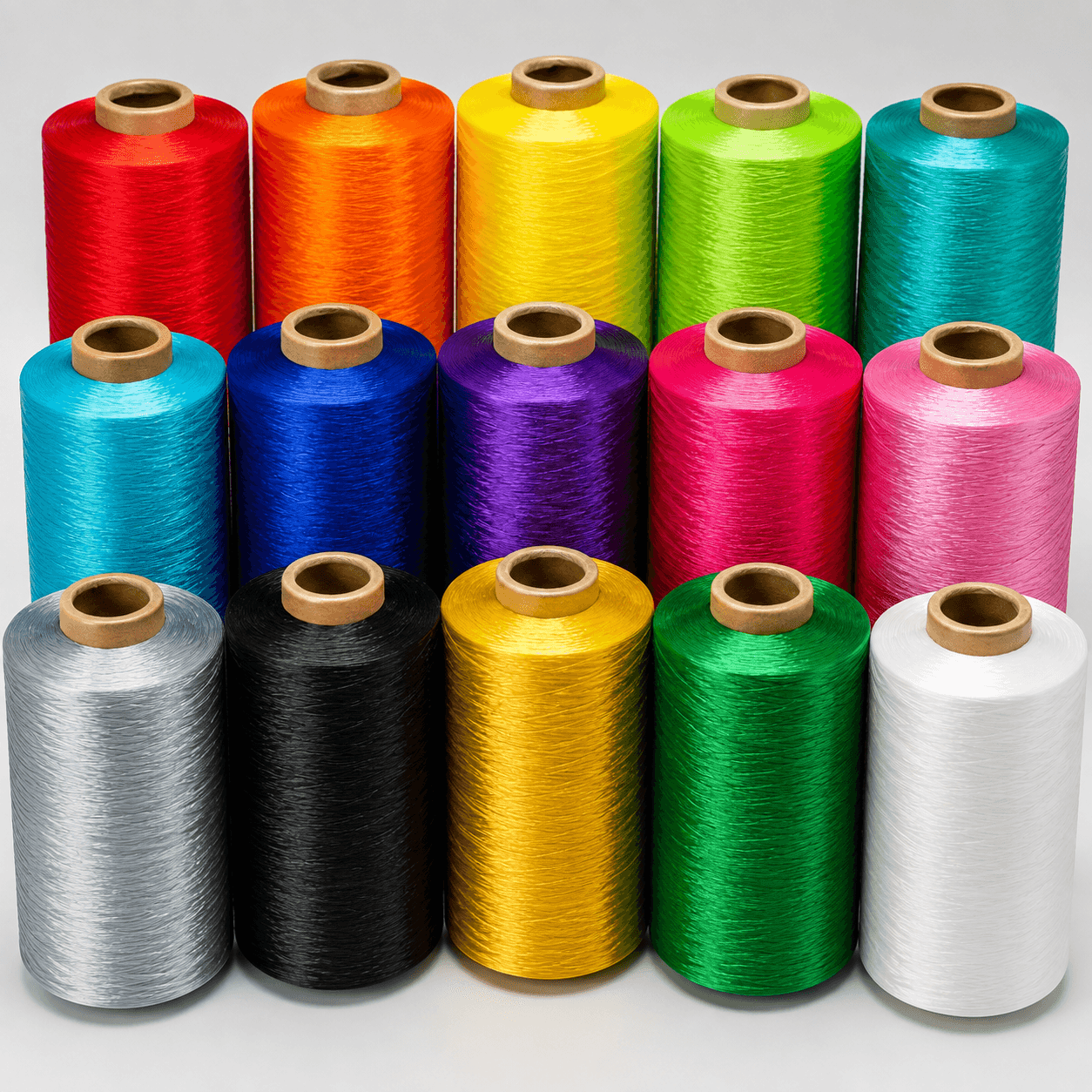 Fifteen large spools of vibrant thread in various colors arranged in three neat rows.